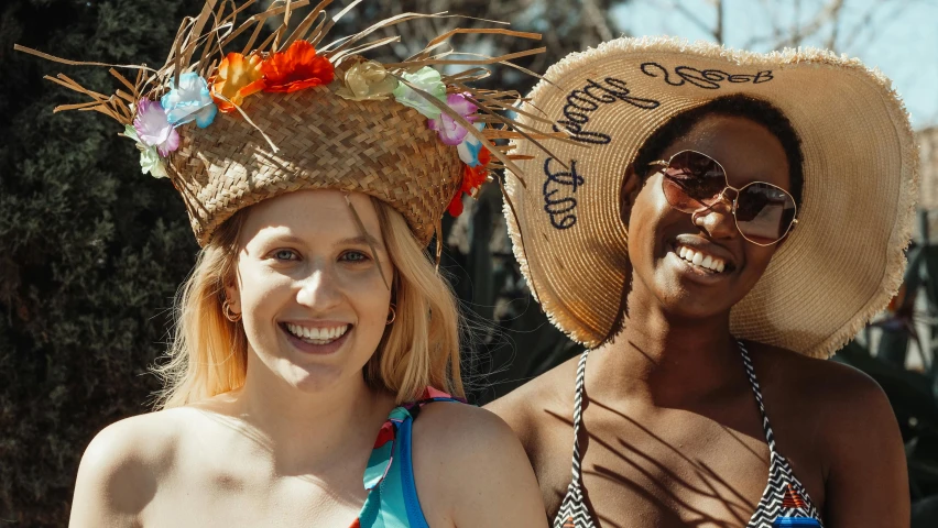 a couple of women standing next to each other, trending on unsplash, wearing straw hat, diverse costumes, on a hot australian day, smiling into the camera