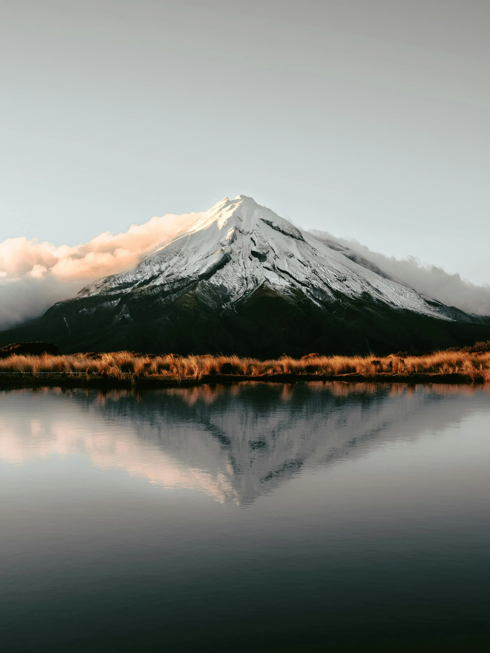 a body of water with a mountain in the background, by Peter Churcher, unsplash contest winner, hurufiyya, mount doom, mirrored, with snow on its peak, highly polished