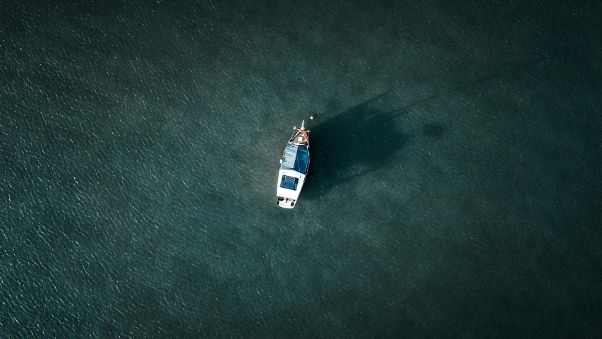 a small boat in the middle of a large body of water, by Adam Marczyński, unsplash contest winner, game top down view, looking sad, deep colour, moored