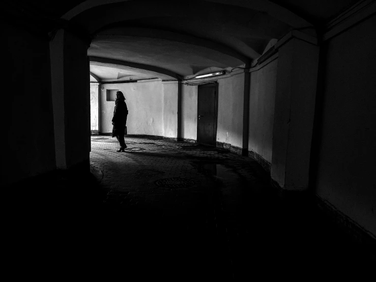 a black and white photo of a person in a dark hallway, by Mirko Rački, unsplash, conceptual art, underground city, woman silhouette, abandoned, instagram picture