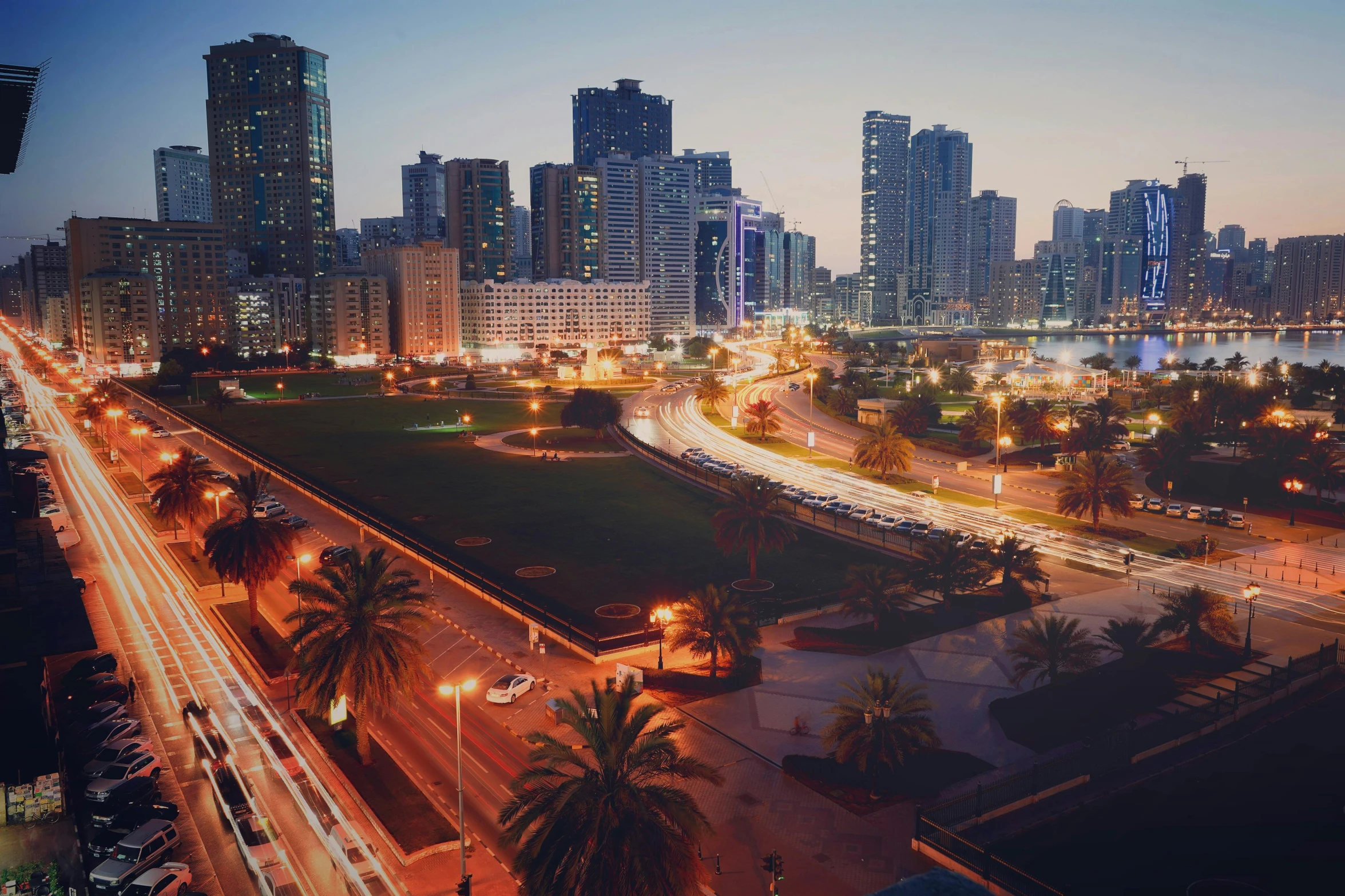 an aerial view of a city at night, pexels contest winner, hurufiyya, oman, skyscrapers with greenery, 1 9 7 0 s photo, grass field surrounding the city