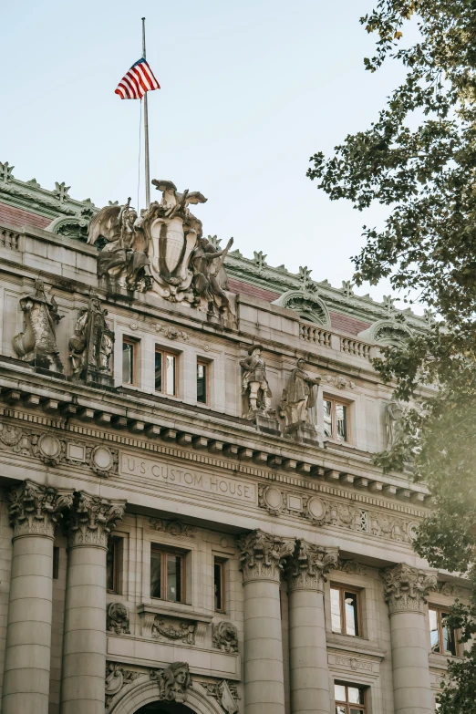 a large building with a flag on top of it, inspired by José Malhoa, neoclassicism, golden hour in manhattan, beautiful sculpted details, an overgrown library, 1910s architecture