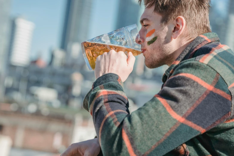 a man drinking a glass of beer in front of a city skyline, by Adam Marczyński, sunny day time, profile image