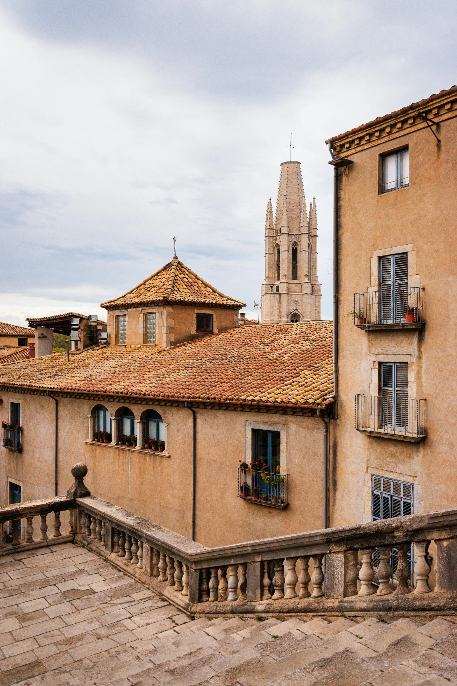 a couple of buildings that are next to each other, inspired by Luis Paret y Alcazar, trending on unsplash, romanesque, balcony, frank gehry, wide high angle view, stone roof