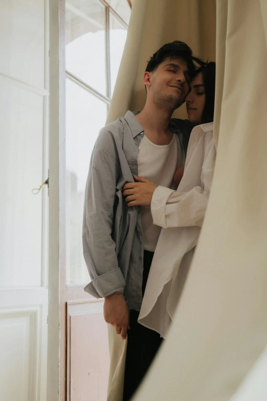 a man and a woman standing next to each other, a picture, by Elsa Bleda, pexels contest winner, romanticism, bedroom, long shirt, happy cozy feelings, white hue