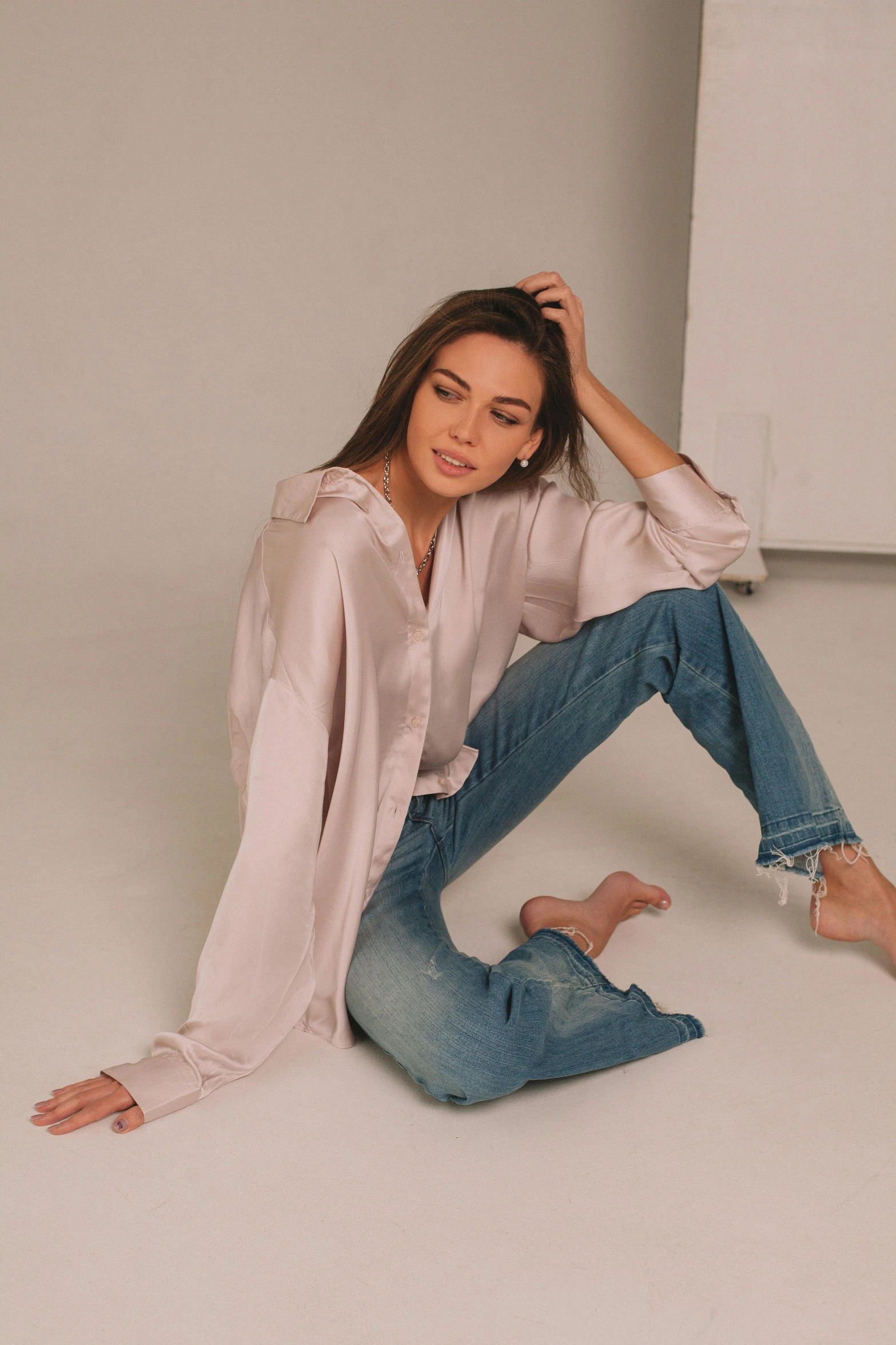 a woman sitting on the floor with her legs crossed, trending on instagram, clothed in silk, wearing a shirt and a jean, draped in silk, wearing a linen shirt