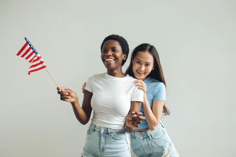 two women standing next to each other holding an american flag, pexels, diverse ages, background image, everyone having fun, instagram photo