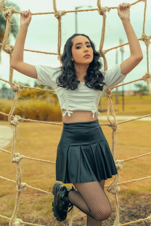 a woman posing in front of a rope net, inspired by Rudy Siswanto, instagram, wearing crop top and miniskirt, postprocessed), wearing leather, gif