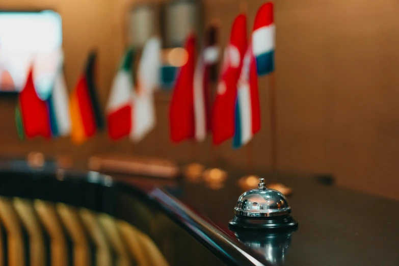 a hotel bell in front of a row of flags, pexels contest winner, happening, at the counter, thumbnail, ready for a meeting, yulia nevskaya