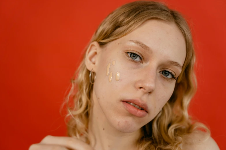a woman holding a banana in front of her face, an album cover, inspired by Elsa Bleda, trending on pexels, hyperrealism, red birthmark, sydney sweeney, layed on a red velvet fabric, huge earrings and queer make up