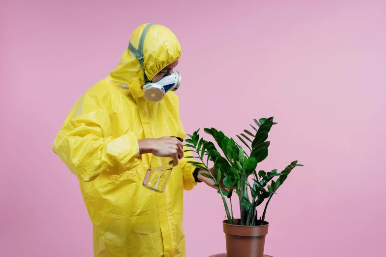 a man in a yellow hazmat suit standing next to a potted plant, pexels contest winner, pink, experimenting, off - white collection, wearing gloves