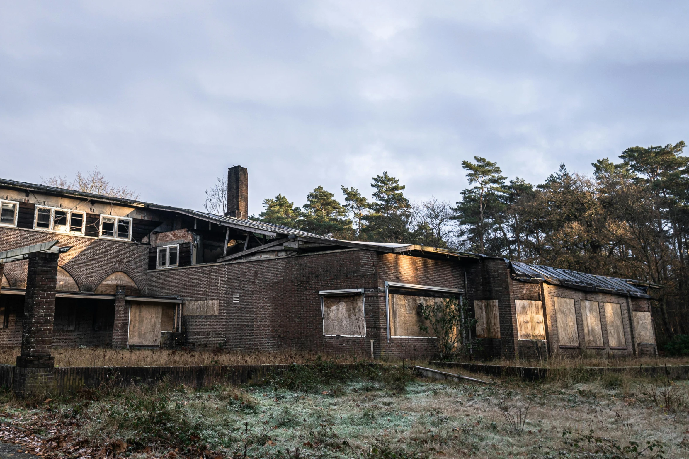 an abandoned house sitting in the middle of a field, by Jan Tengnagel, unsplash, brutalism, roofed forest, hospital, lit from the side, brown