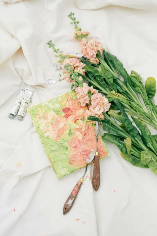 a bunch of flowers sitting on top of a bed, a detailed painting, inspired by Art Green, process art, on a white background, holding paintbrushes, green and pink fabric, al fresco