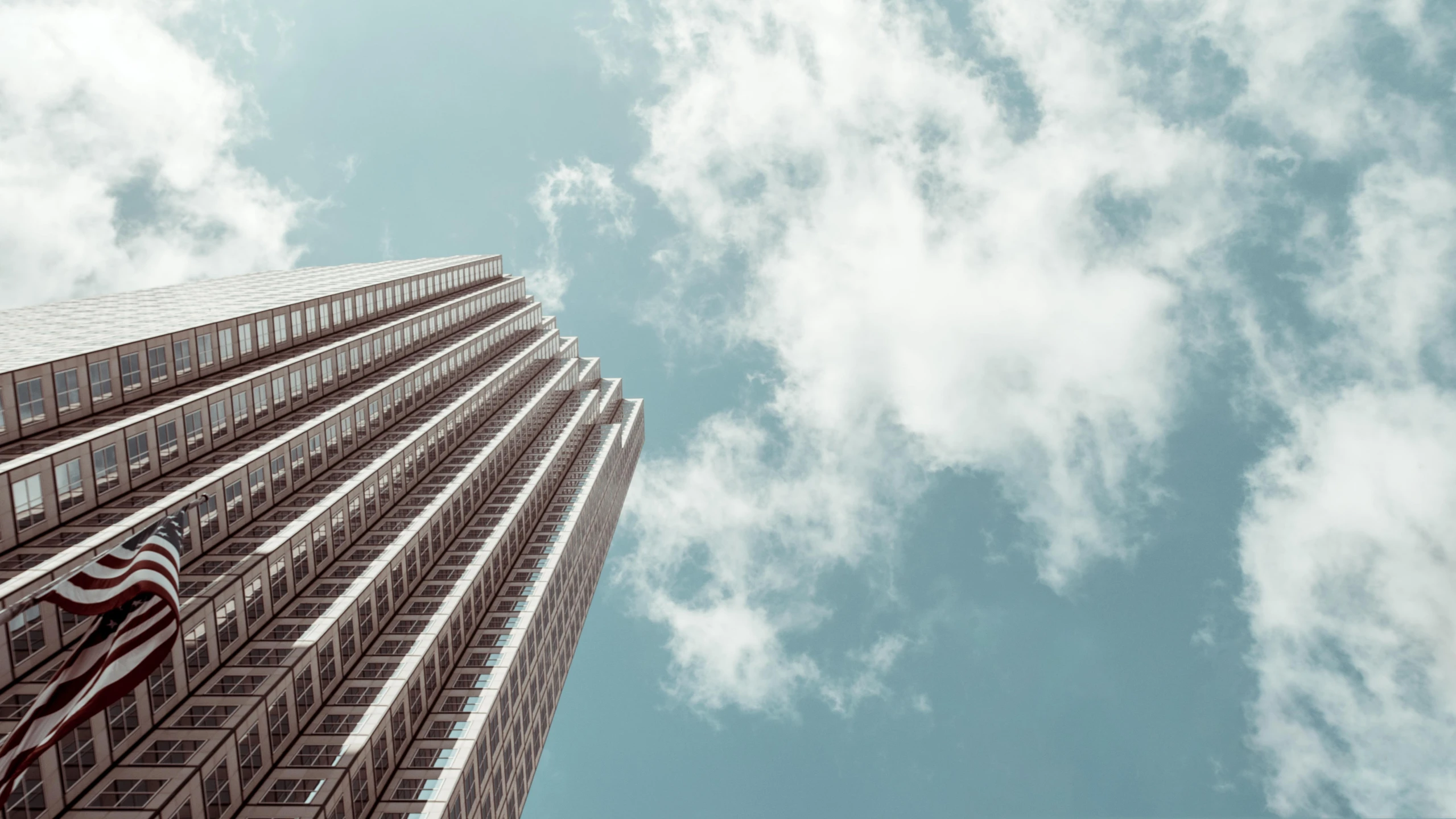 a tall building with a clock on the side of it, inspired by Ricardo Bofill, pexels contest winner, brutalism, tall fluffy clouds, view from bottom to top, mies van der rohe, plain uniform sky