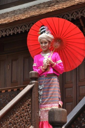 a woman in a pink dress holding a red umbrella, sumatraism, wearing an elegant tribal outfit, slide show, touring, multiple stories