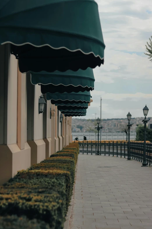 a row of green awnings on the side of a building, a picture, by Ismail Acar, trending on unsplash, visual art, royal palace near the lake, gif, mall background, turkish and russian