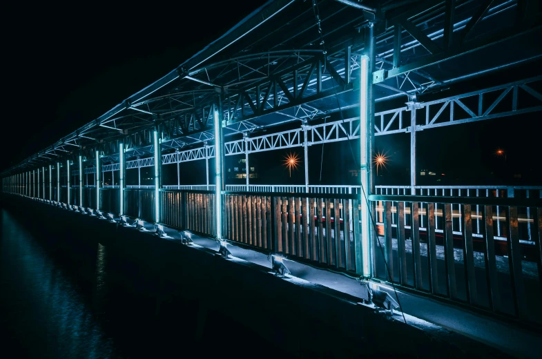 a bridge over a body of water at night, an album cover, inspired by Elsa Bleda, unsplash contest winner, graffiti, train station, blue neon, azamat khairov, industrial lighting