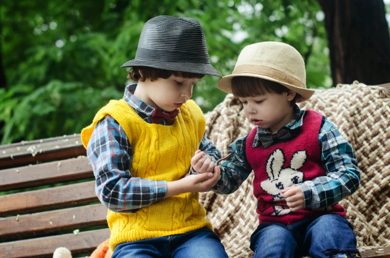 a couple of young boys sitting on top of a wooden bench, pexels, knitted hat, precious gems, having a picnic, oscar winning