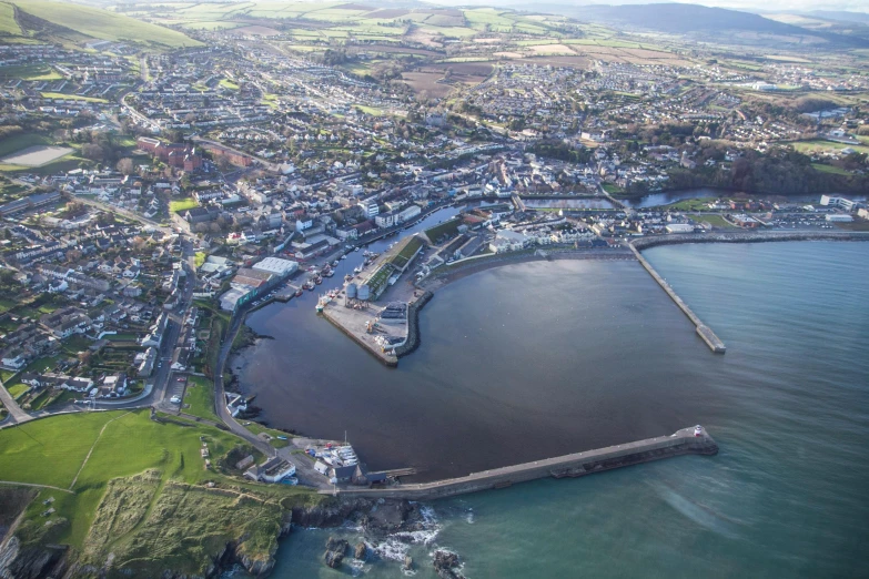 a large body of water next to a lush green hillside, by Thomas Furlong, pexels contest winner, happening, harbour, maryport, aerial view of a city, listing image