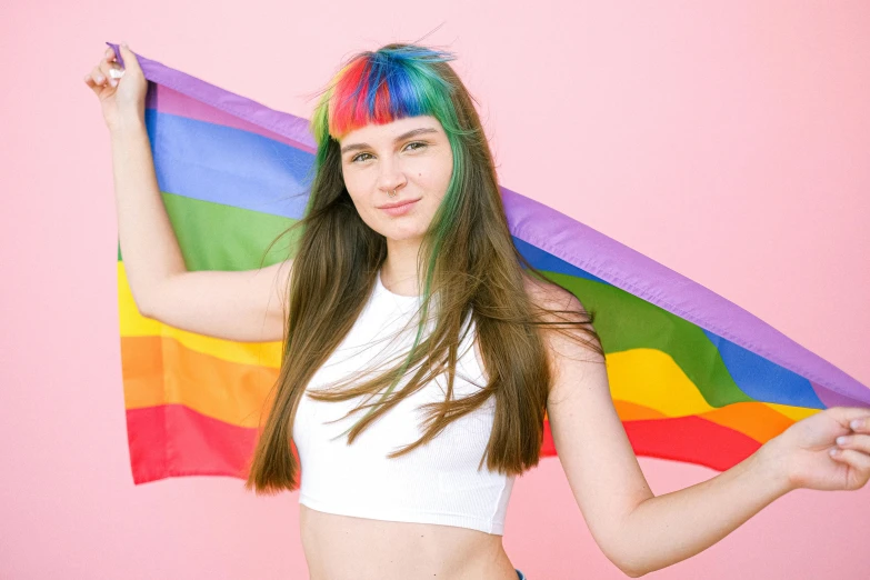 a woman with colorful hair holding a rainbow flag, trending on pexels, brown hair with bangs, 1 6 years old, colorful]”, handsome girl
