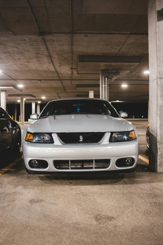 two cars parked next to each other in a parking garage, by Adam Rex, pexels contest winner, with a white muzzle, mustang, late 2000’s, square nose