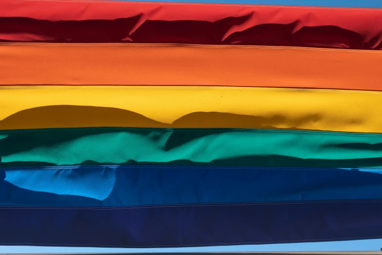 a rainbow flag blowing in the wind on a sunny day, inspired by Jan Rustem, unsplash, color field, several layers of fabric, blue and yellow ribbons, close-up, 5 colors