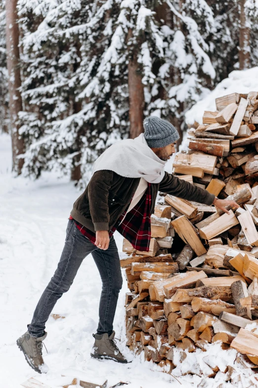 a man standing next to a pile of wood in the snow, by Julia Pishtar, pexels contest winner, dancing around a fire, reclaimed lumber, bulky build, handsome male