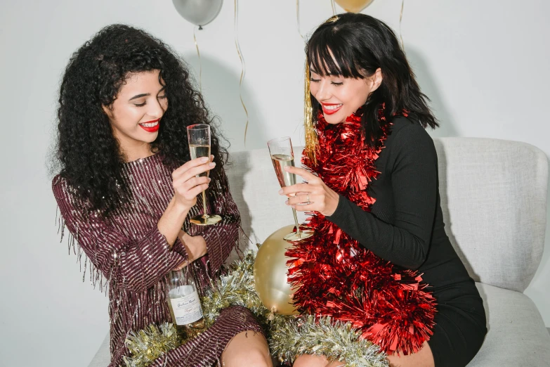 a couple of women sitting on top of a couch next to each other, pexels, happening, new years eve, on a white table, brunette, 🐿🍸🍋