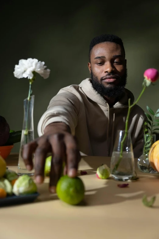 a man sitting at a table with fruit and flowers, jaylen brown, holding it out to the camera, rubens, maximus jacobs