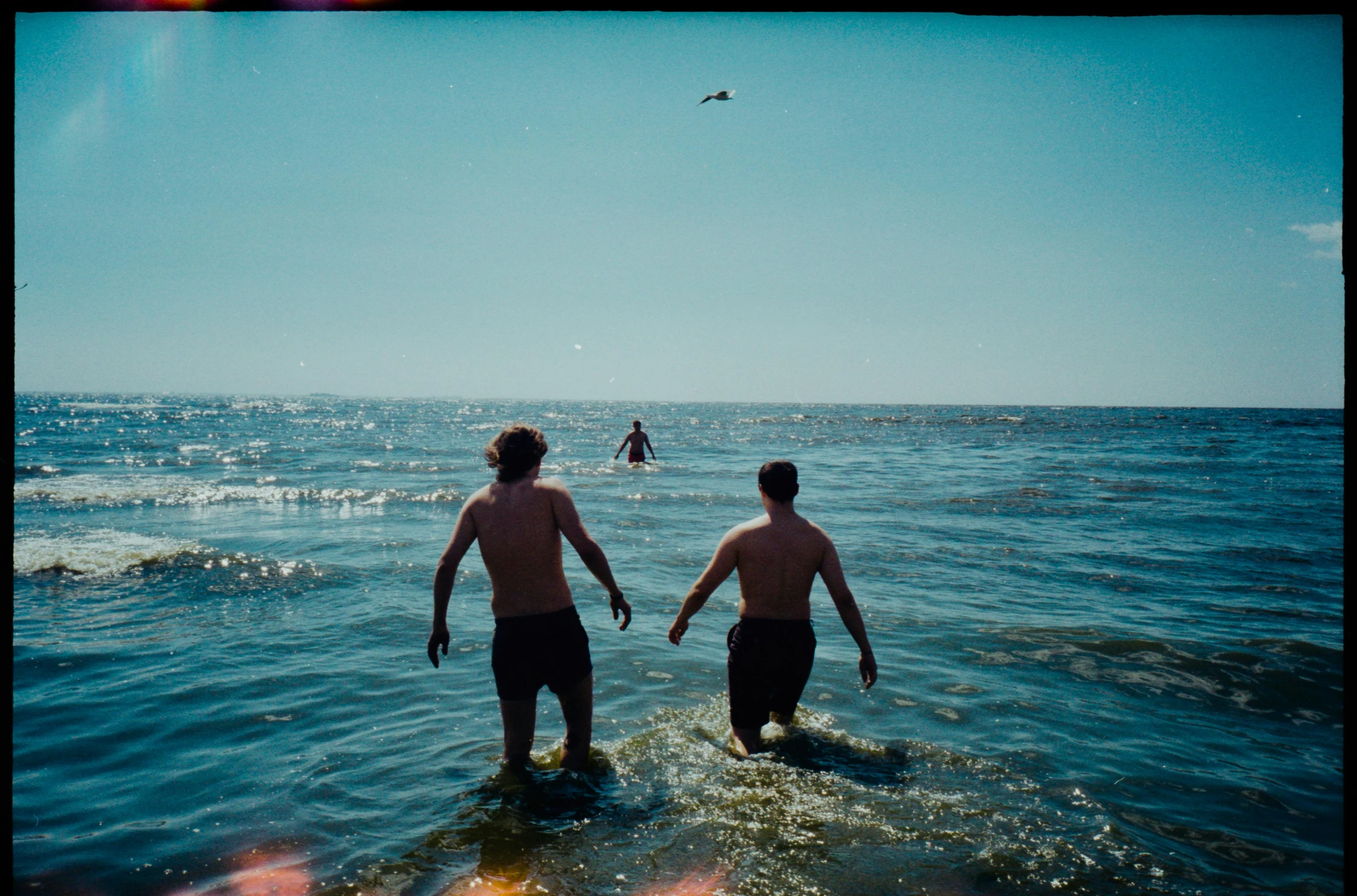 a couple of people that are standing in the water, a polaroid photo, unsplash, two young men, swimming in ocean, ignant, black sea