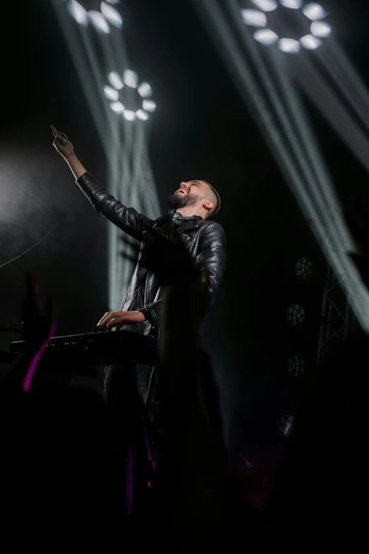 a man standing on top of a stage holding a microphone, by Tom Bonson, pexels, synthetism, dressed in black leather, flume, keyboardist, singer maluma