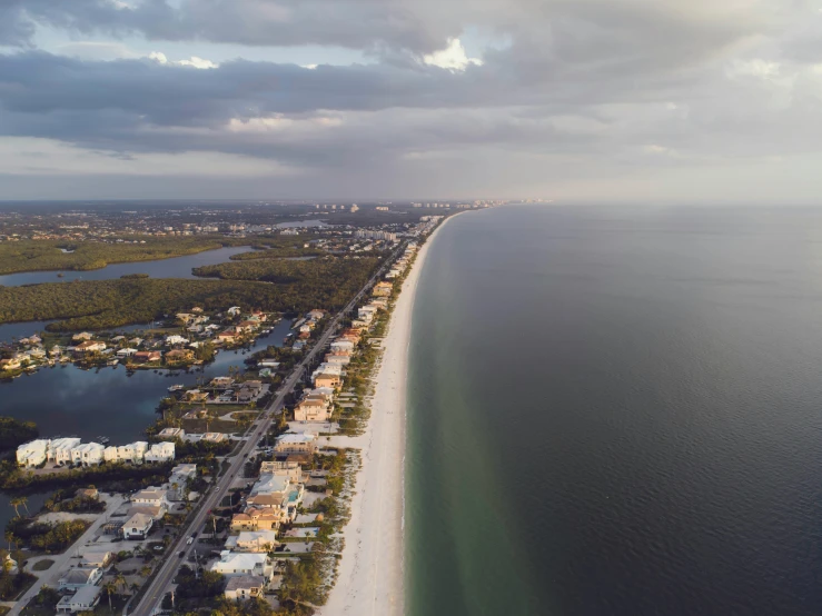 a large body of water next to a beach, by Ryan Pancoast, unsplash contest winner, photorealism, naples, airborne view, sunset beach, neighborhood