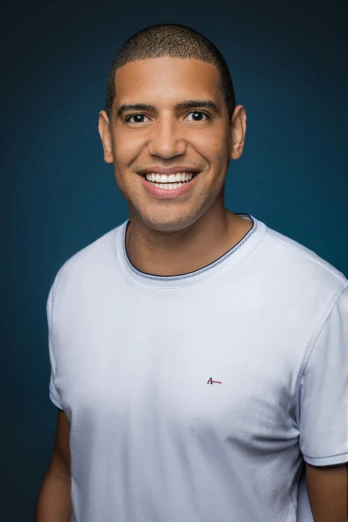 a man in a white shirt posing for a picture, with a blue background, ariel perez, smiling male, dark backdrop