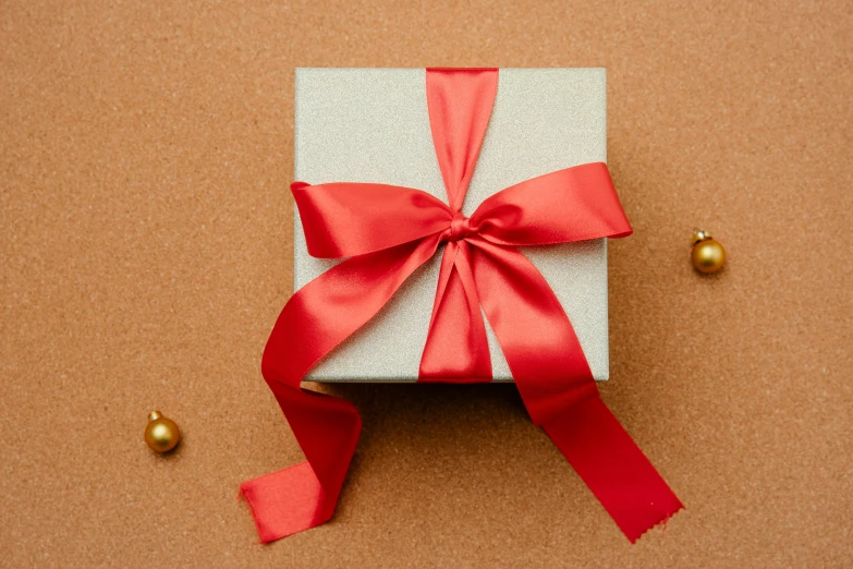 a white box with a red ribbon tied around it, by Julia Pishtar, pexels contest winner, relaxed. gold background, red brown and grey color scheme, toy package, thumbnail