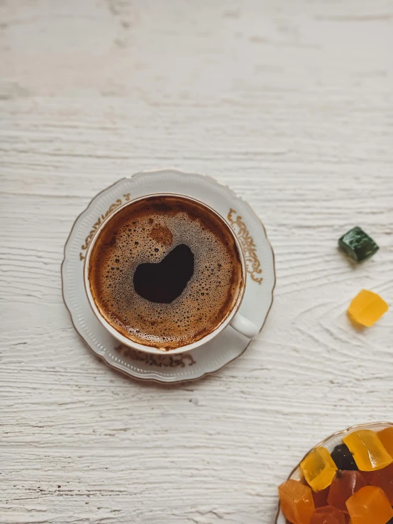 a cup of coffee and a donut on a table, inspired by Géza Mészöly, hurufiyya, embedded with gemstones, gif, brown, medium close shot