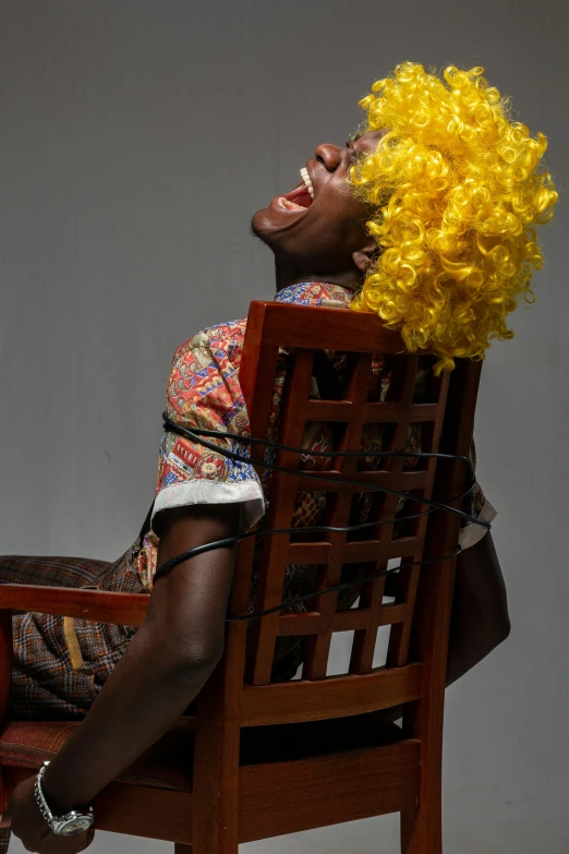 a man with a yellow wig sitting in a chair, photo of a black woman, head bent back in laughter, tied with chair, yan gisuka