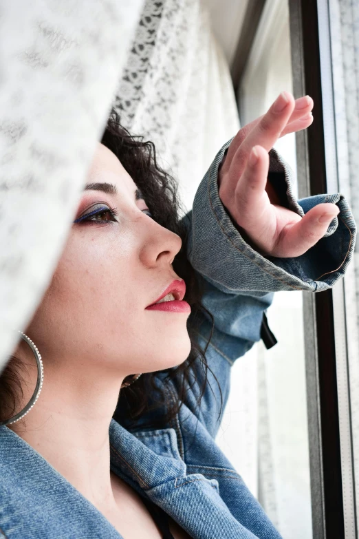 a woman is looking out of a window, an album cover, trending on pexels, pale-skinned persian girl, heavy gesture style closeup, low quality photo, casual pose