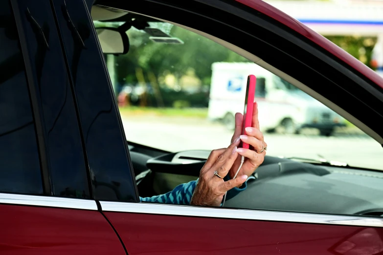 a man sitting in a car with a cell phone in his hand, a picture, by Michael Goldberg, shutterstock, happening, square, red car, instagram story, older male