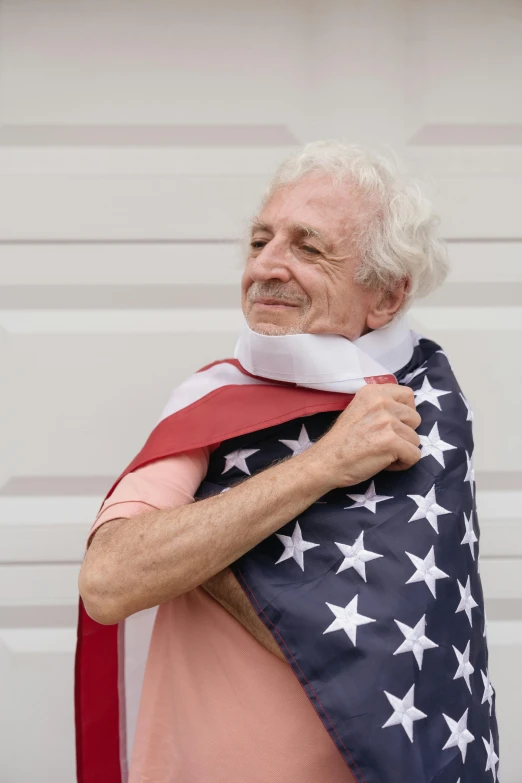 a man holding an american flag in front of a garage door, by Alison Geissler, trending on reddit, relaxed dwarf with white hair, portrait of an old, man wearing a closed cowl, celebration