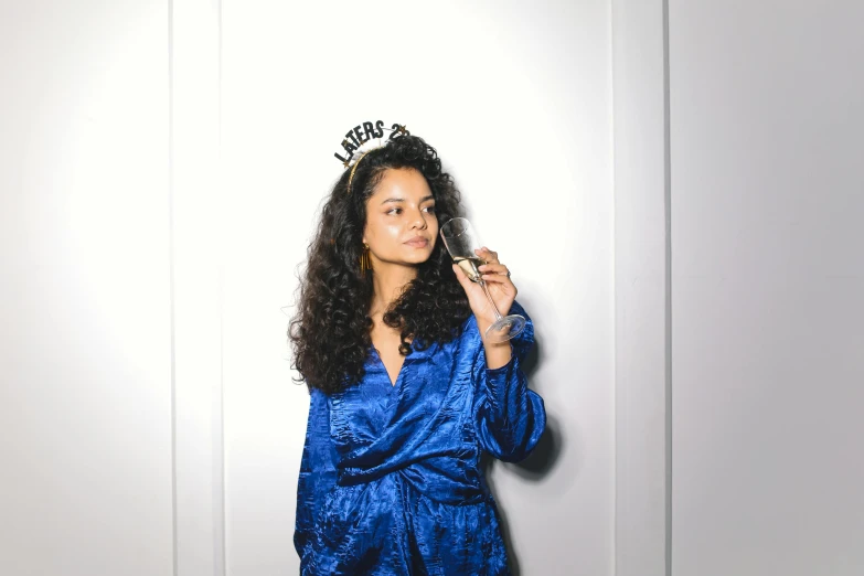 a woman in a blue robe holding a cell phone, an album cover, pexels, renaissance, black long curly hair, wearing a party hat, wearing a tiara, ((blue))