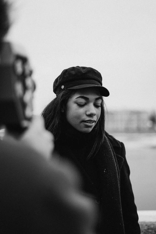 a black and white photo of a woman wearing a hat, a black and white photo, unsplash, aida muluneh, movie footage, holding microphone, instagram picture