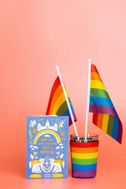 a cup with a rainbow flag next to it, by Julia Pishtar, dada, greeting card