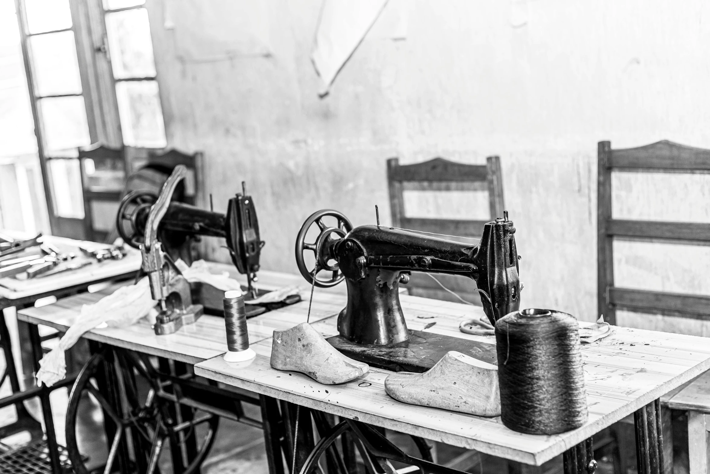 a sewing machine sitting on top of a wooden table, a black and white photo, workers, mannequins, restoration, uploaded