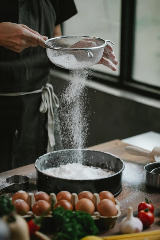 a person pouring flour into a pan on a table, pexels contest winner, vertical orientation, bubbling liquids, pastry, sand particles