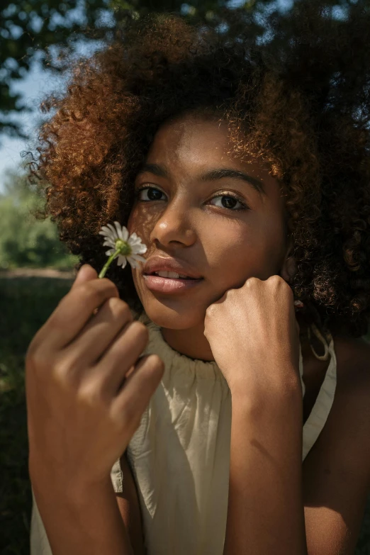 a woman with a flower in her hand, trending on unsplash, renaissance, brown skin. light makeup, in nature, medium format, curly haired