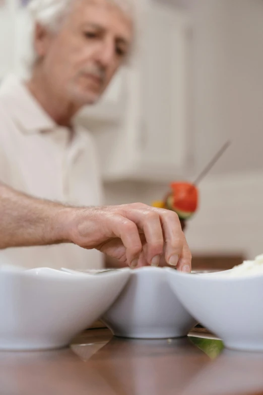 a man sitting at a table with two bowls of food, chopping hands, close - up photograph, porcelain, ergonomic