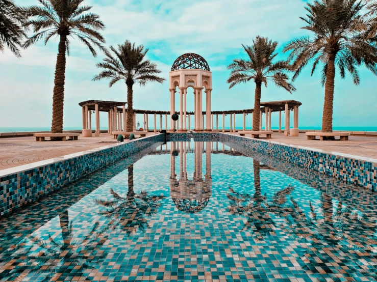 a pool surrounded by palm trees next to the ocean, an album cover, pexels contest winner, baroque, persian style architecture, dubai, ornate tiled architecture, unsplash photo contest winner