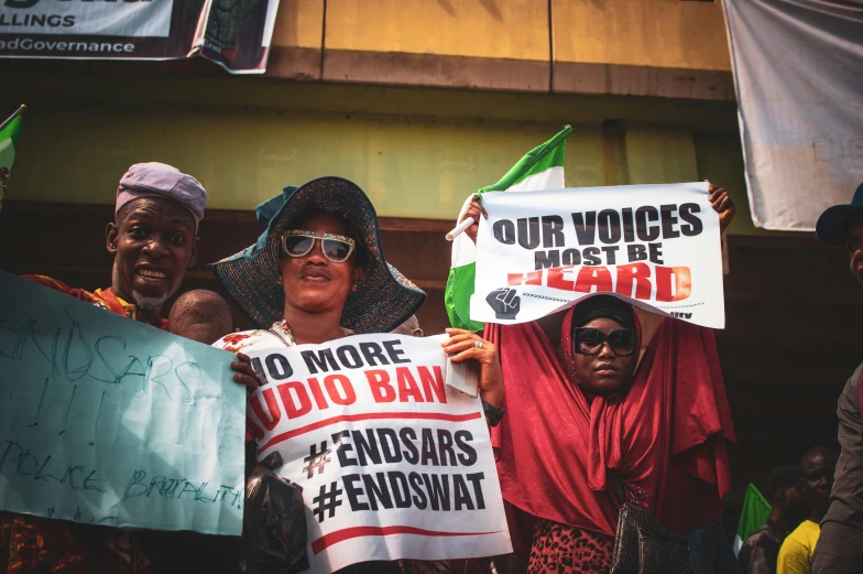 a group of people holding signs in front of a building, by Ingrida Kadaka, adebanji alade, postprocessed, emir, protest