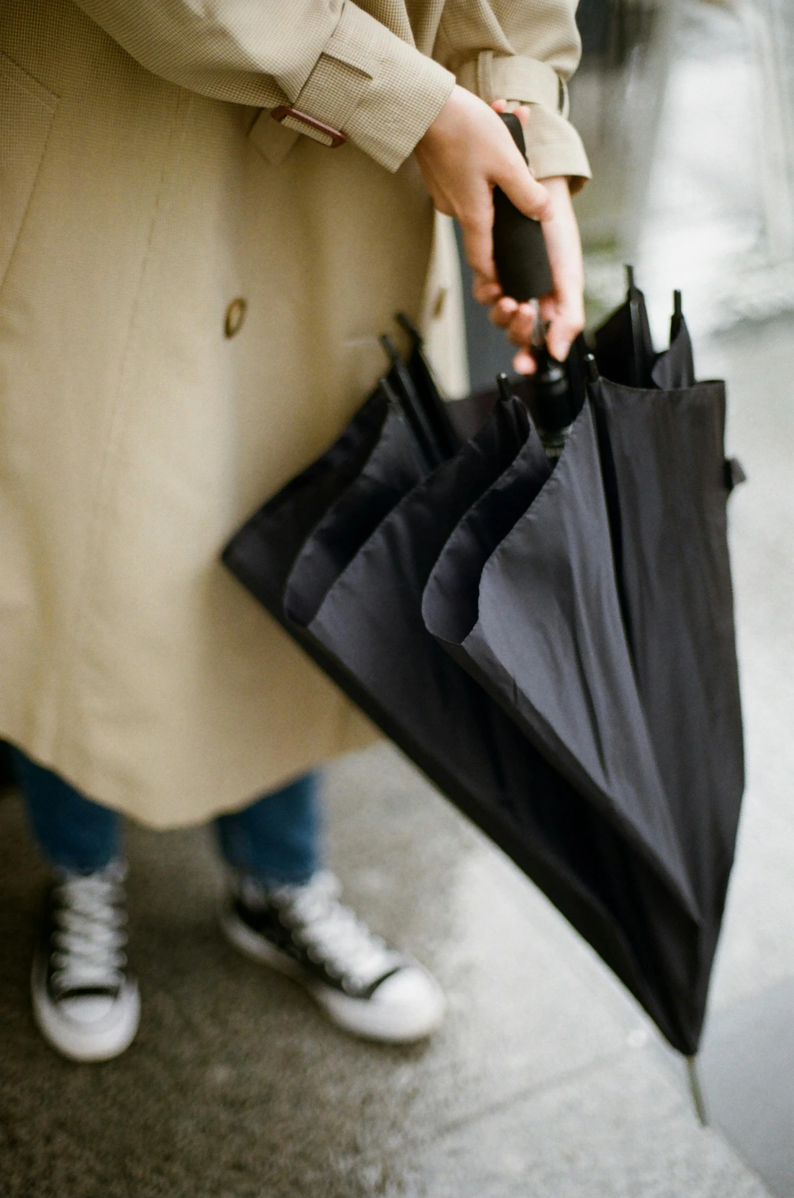 a woman in a trench coat holding an umbrella, by Nina Hamnett, unsplash, all black matte product, detail shot, multiple layers, canopies