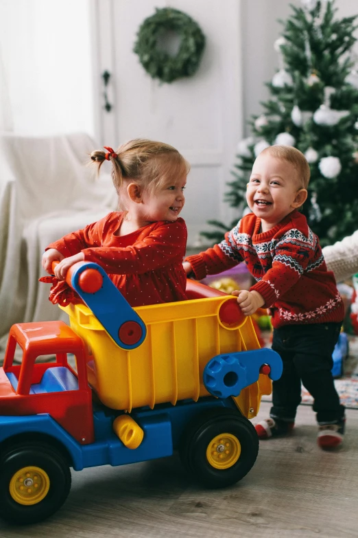 two children playing with a toy truck in front of a christmas tree, inspired by Myles Birket Foster, pexels contest winner, a still of a happy, gif, softplay, fisher price